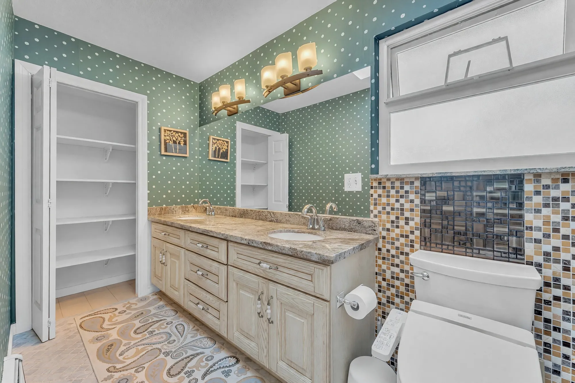 The upper bathroom: a double vanity in granite, a glass-tile backsplash, a linen closet with open shelves