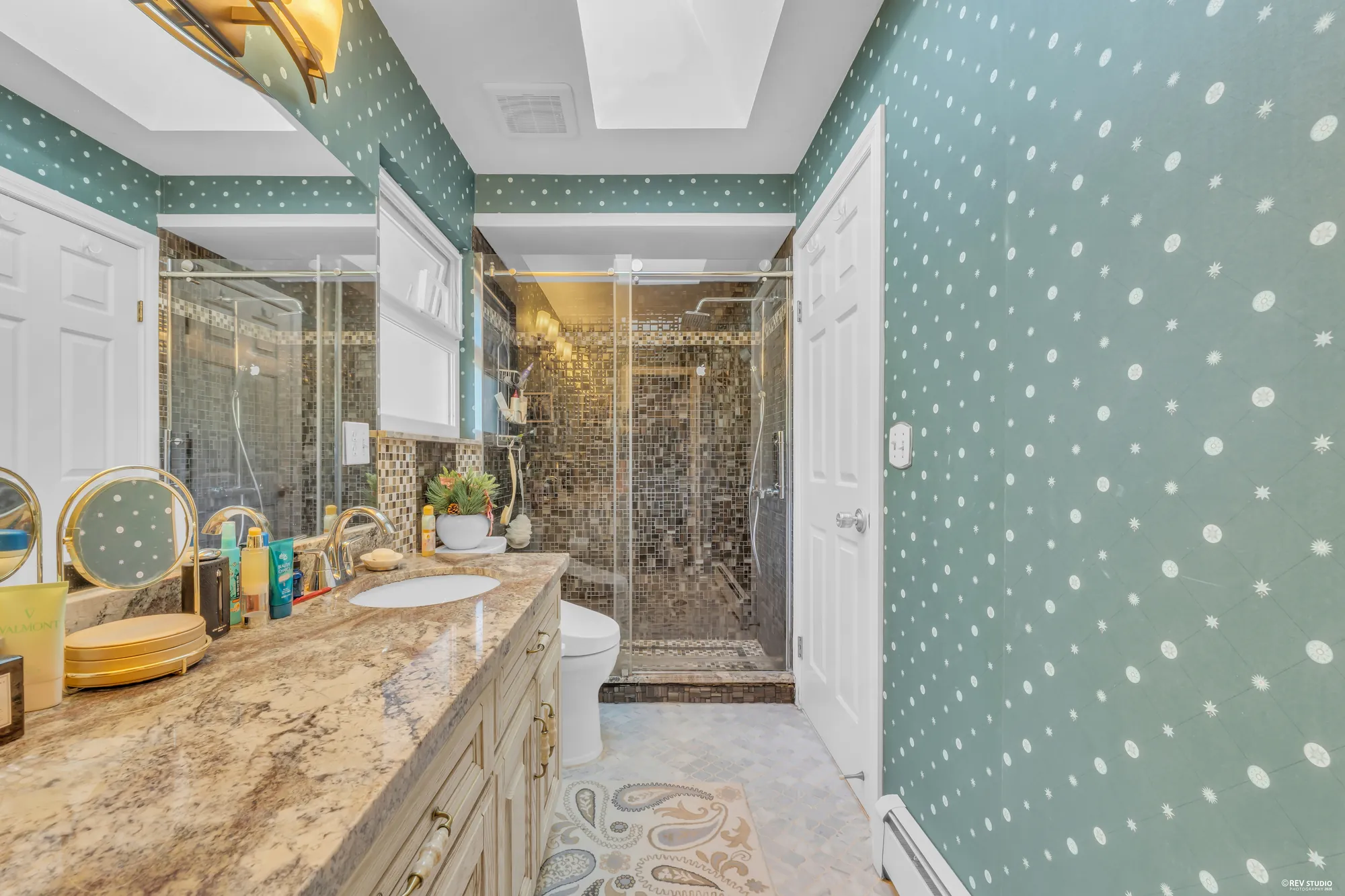 The upper bathroom's glass shower in mosaic tile, the vanity beside it