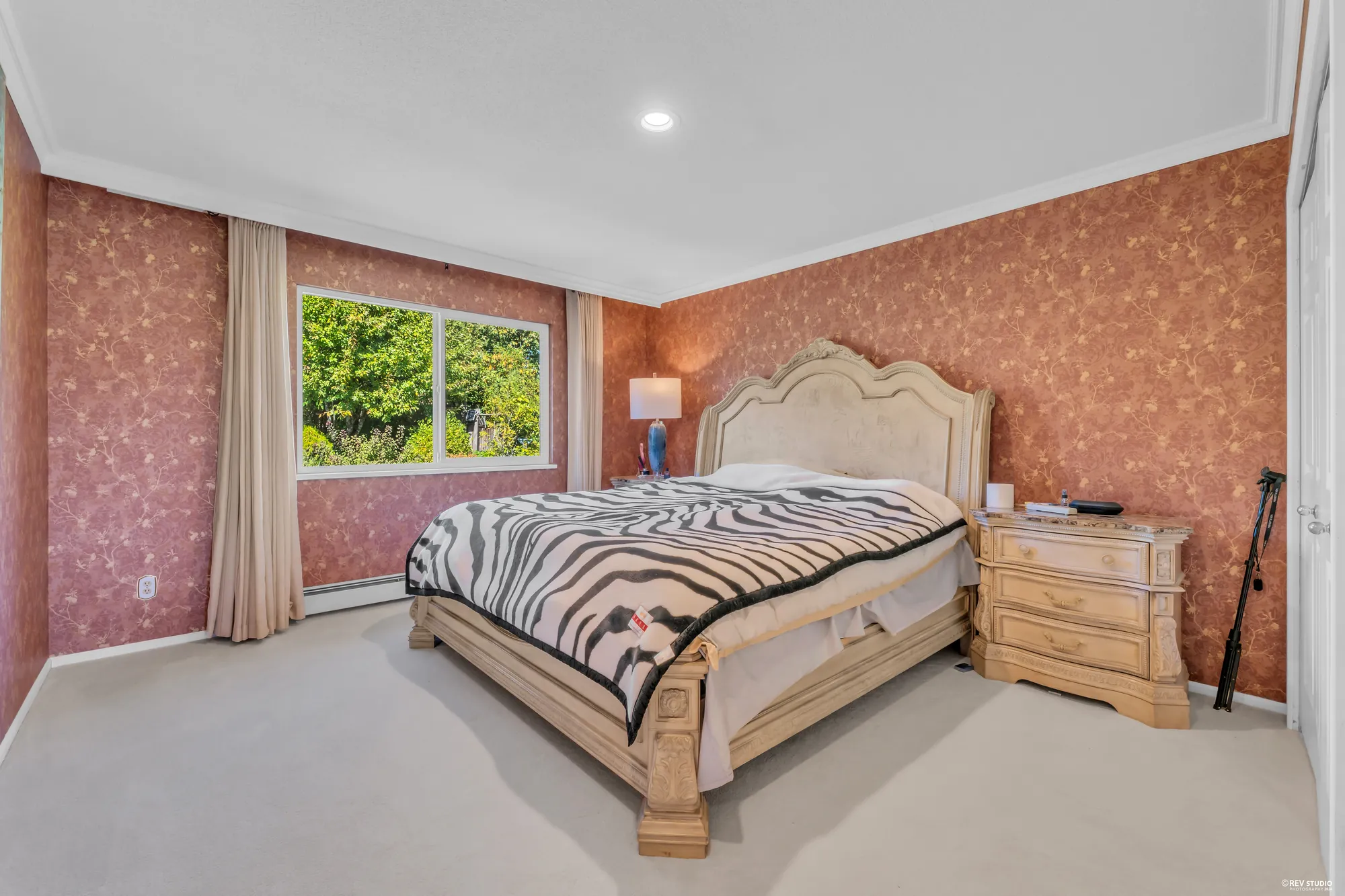 A bedroom in pink with a bed, night tables and a window