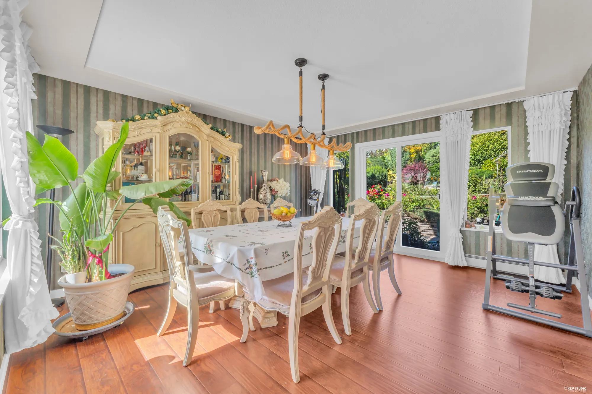 The dining room: a table and chairs under two pendants, a china cabinet, a door to the deck, hardwood