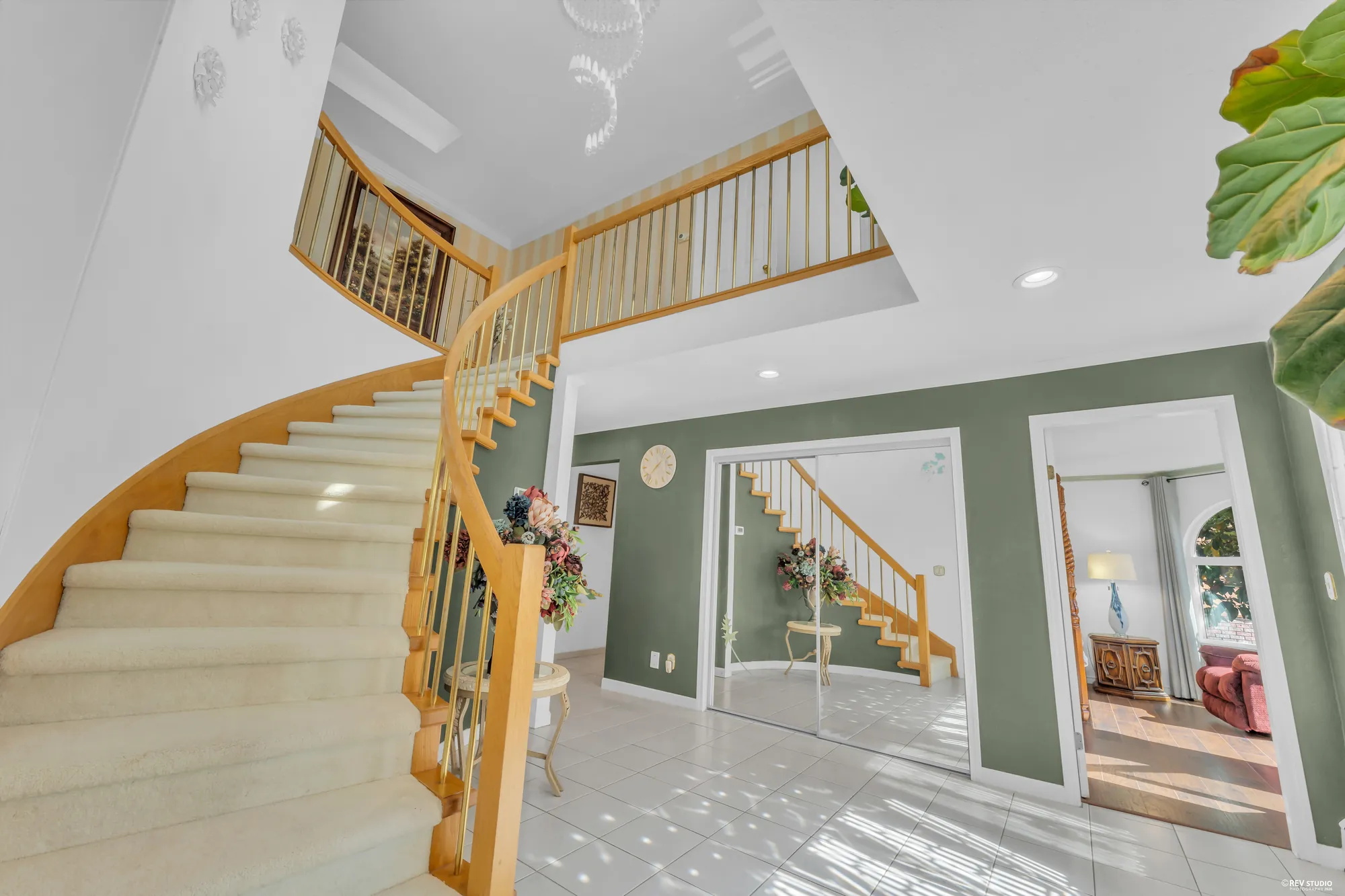The stair from the front door, the landing above, the rooms beyond the arches