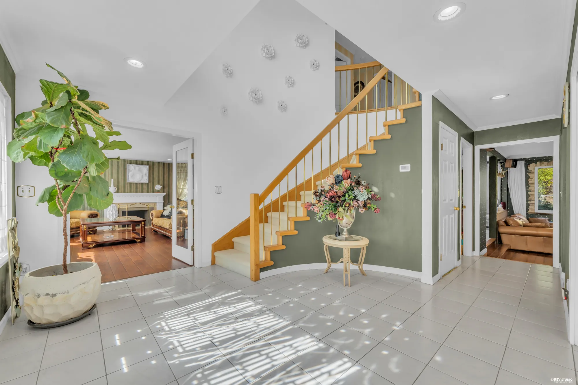 The foyer from the living room side: the stair, a fig tree, the hall to the family room