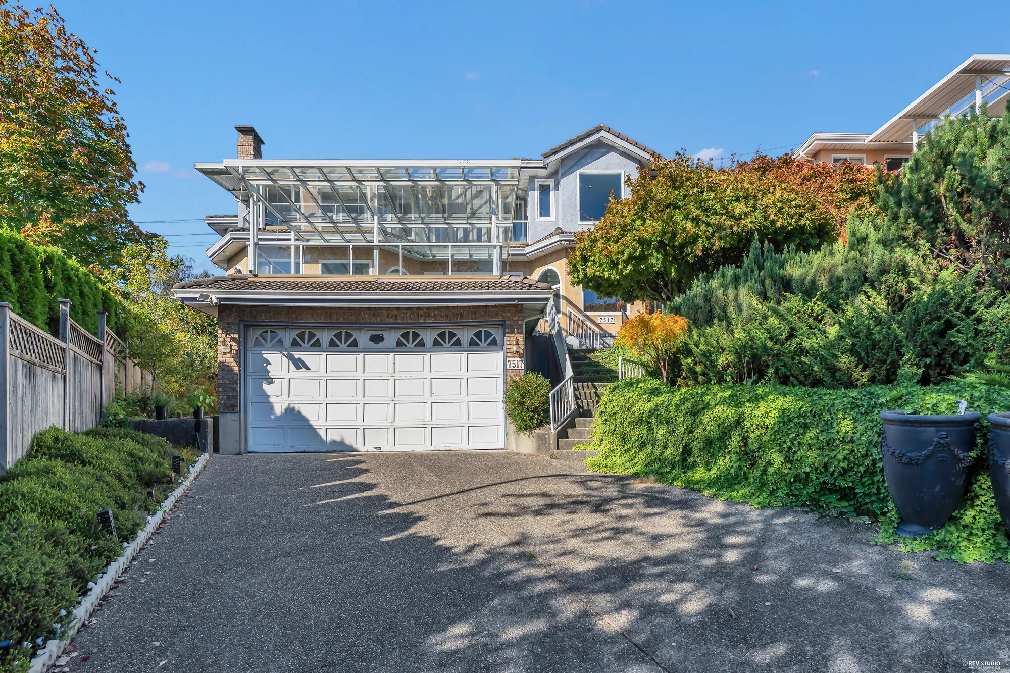 The driveway and the garage from the street, the terrace's glass roof above, the stair on the right