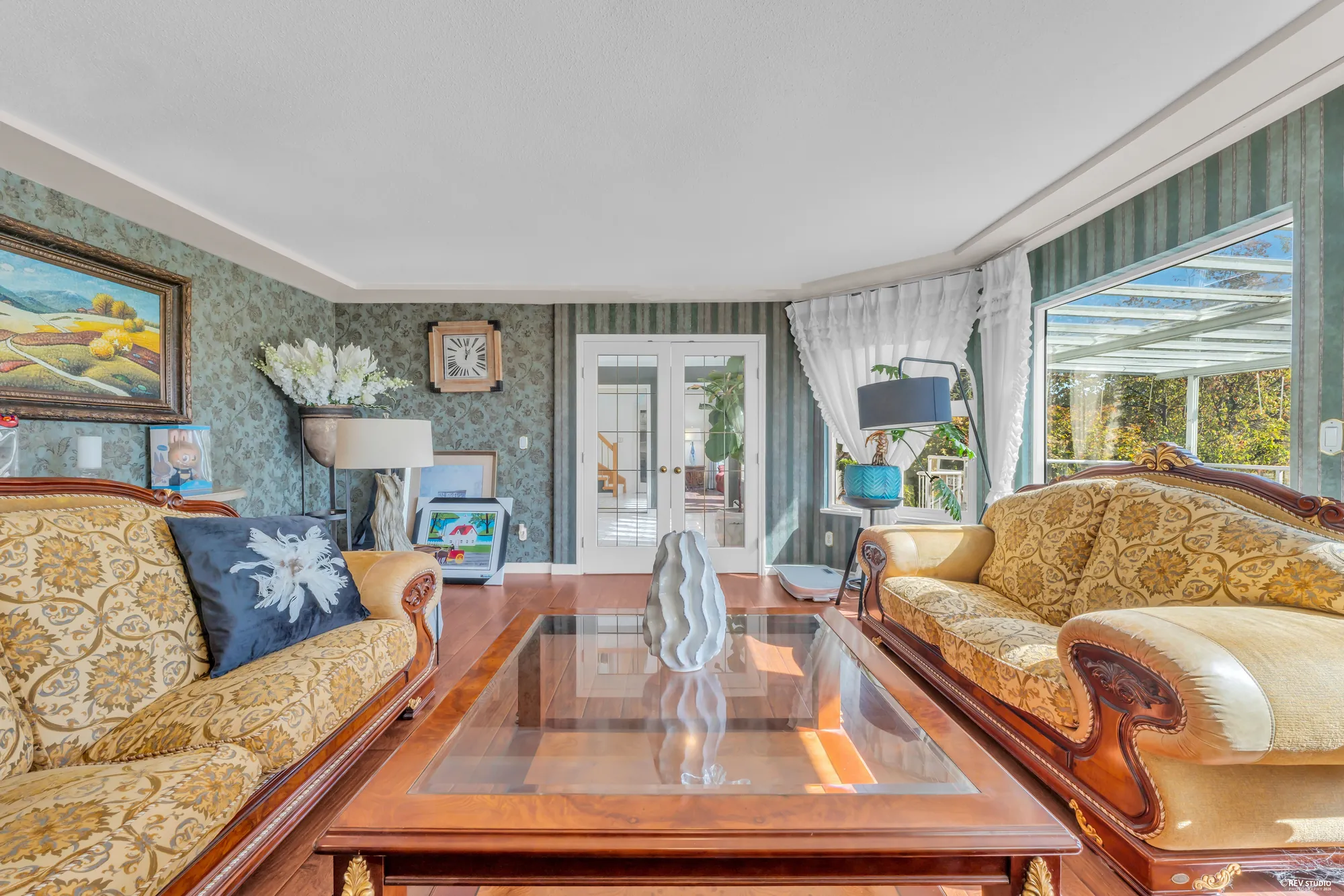 The living room: gold sofas on hardwood, a fireplace with a white mantel, the bay window at the front