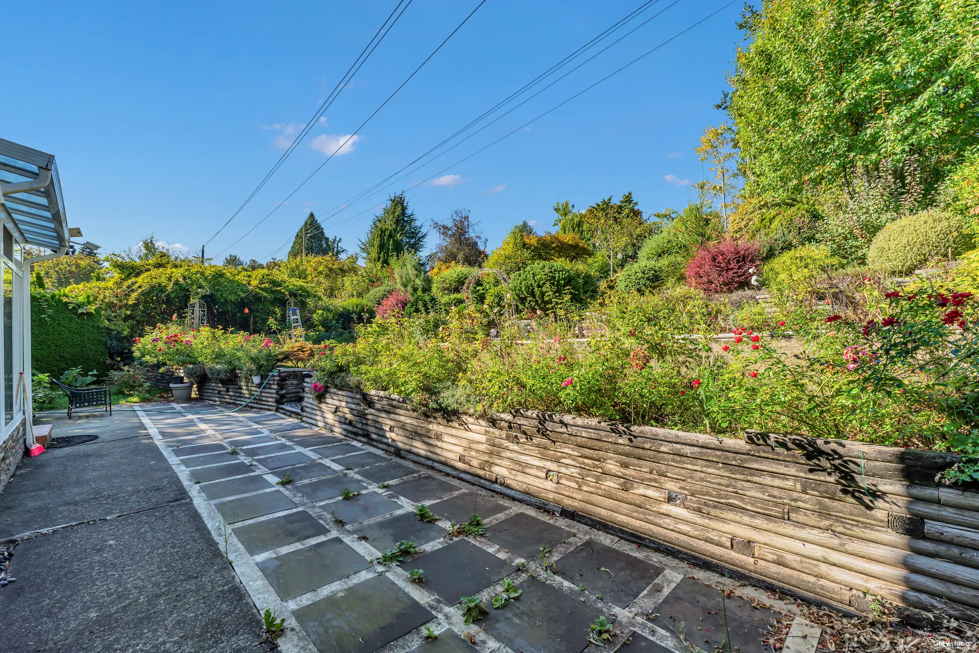 The paved side of the terrace with a rock garden and planters along a low wall