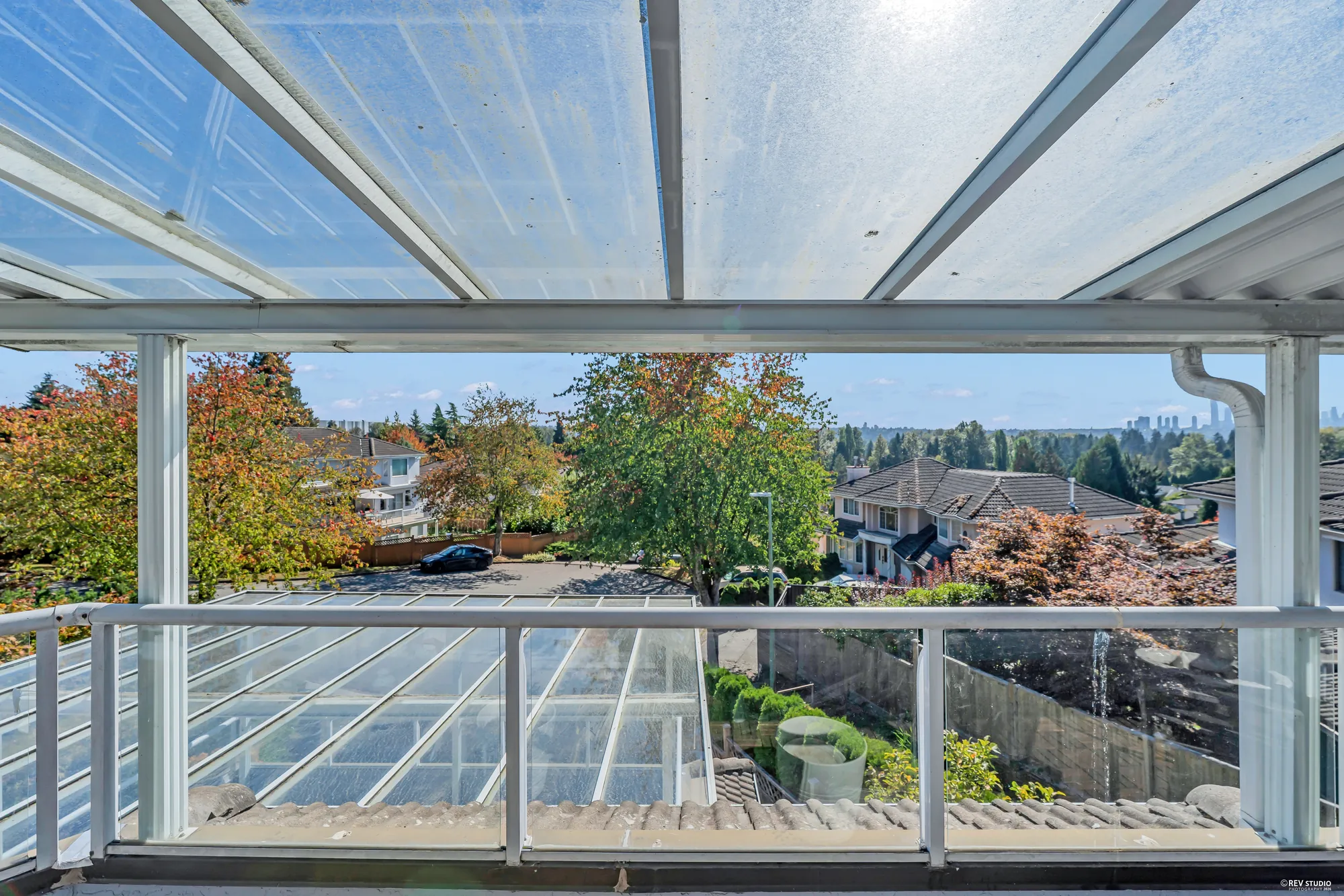 From the terrace: the rooftops of the neighbourhood, trees, and the towers of downtown Vancouver small on the skyline